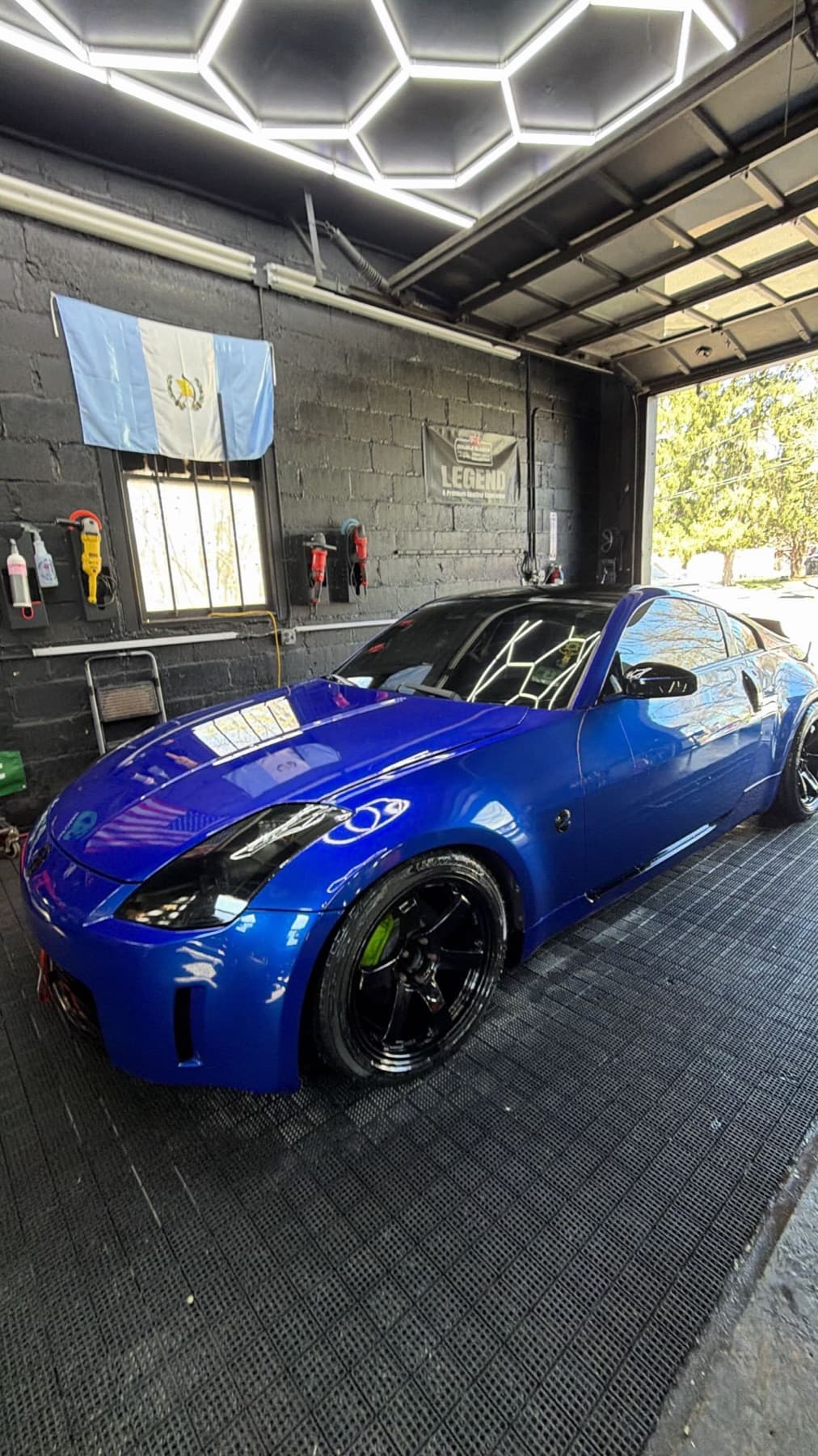 Inside the Insane Auto Detailing shop, a car under shop lights